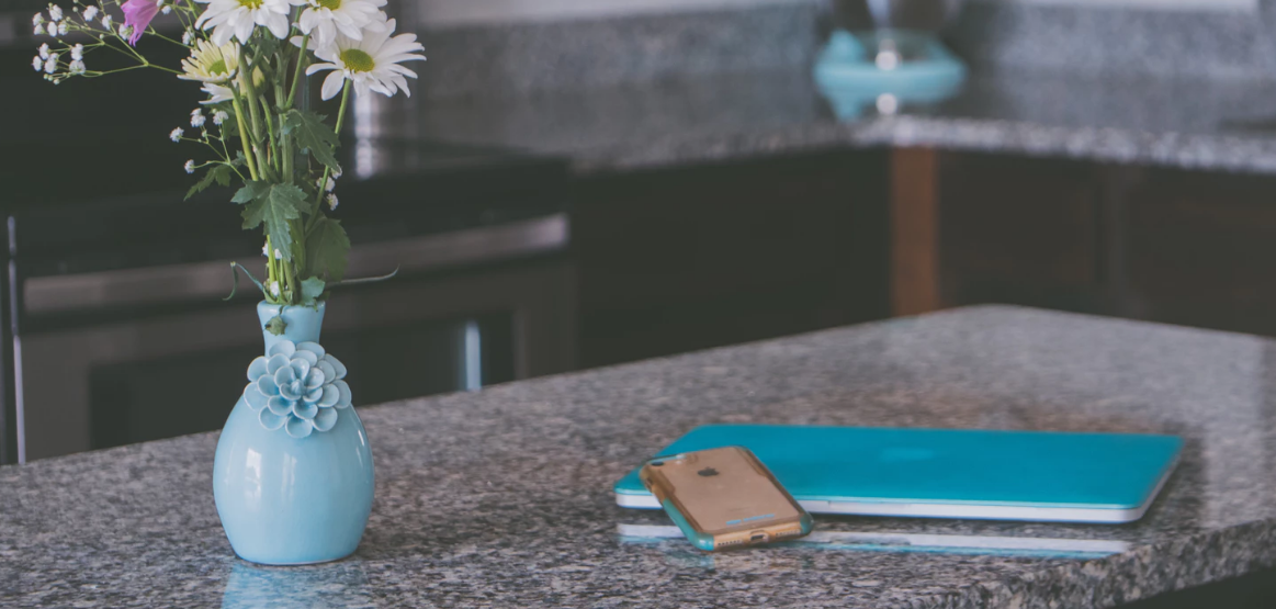 Kitchen counter island with a flower vase, iPhone, and notepad